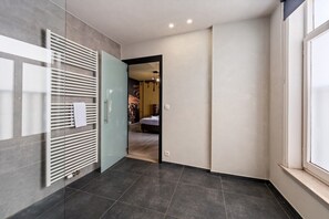 Een moderne gang met een glazen deur die naar een slaapkamer leidt.