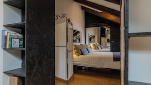 A bedroom with two beds, a dark wooden floor, and a bookshelf with books and a box. - Barbaroux Apartments by Wonderful Italy (Turin)