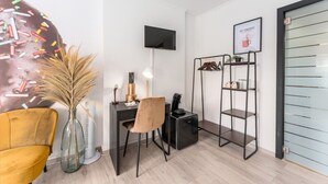 Un espacio de oficina moderno con escritorio, silla, televisor y estante con objetos decorativos.