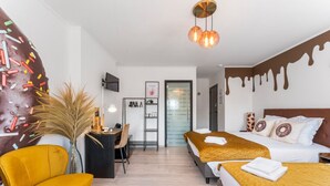 Habitación de hotel con dos camas, un escritorio, una silla y una decoración grande en la pared.