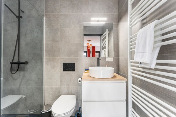 A modern bathroom with a shower, toilet, and sink.