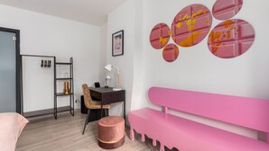 Une chambre à coucher moderne avec un lit, un bureau, une chaise, un banc rose et un mur orné de motifs circulaires.