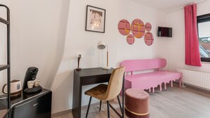 Une chambre moderne équipée d’un bureau, d’une chaise, d’un banc rose et d’un petit pouf rond.