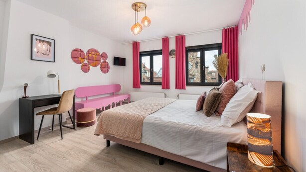 Une chambre moderne avec un lit, un bureau, une chaise et une vue sur la ville.