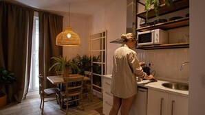 Cocina compacta con zona de comedor, muebles de madera y una lámpara colgante.