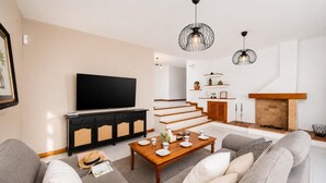 Una sala de estar moderna con una televisión de pantalla plana, una mesa de centro de madera y una chimenea.
