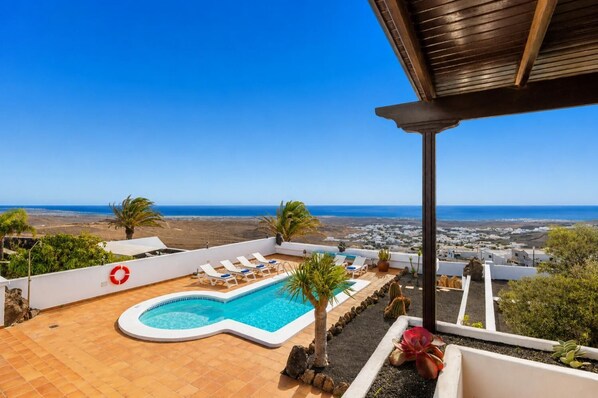A rooftop pool with a clear view of the sea and town.