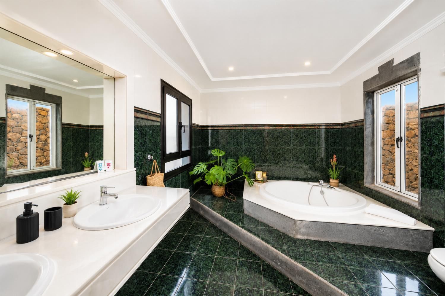 A modern bathroom with two sinks, a large mirror, and a bathtub.