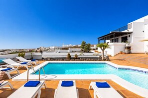 A rooftop pool with lounge chairs and a clear view of the cityscape.