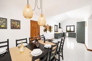 A modern kitchen with a dining area, featuring a large table, chairs, hanging lights, and kitchen cabinets. - Villa Valiente - Four Bedroom Villa, Sleeps 8 (Tías)