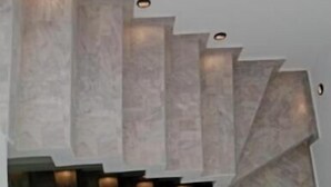 Escadaria em espiral com design moderno, combinando degraus claros e escuros e iluminação embutida.