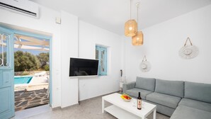Una sala de estar moderna con un sofá gris, una mesa de centro blanca y un televisor de pantalla plana montado en la pared.