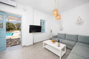 Un salon moderne avec un canapé gris, une table basse blanche et un téléviseur à écran plat fixé au mur.