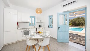 Una cocina moderna con gabinetes blancos y una zona de comedor con una mesa y sillas blancas.