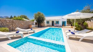 A swimming pool with lounge chairs and a stone wall.
