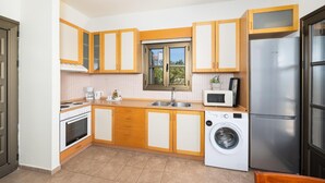 A compact kitchen with a stove, microwave, sink, and washing machine. - Villa Daphne - Two Bedroom Villa, Sleeps 4 (Kalathos)