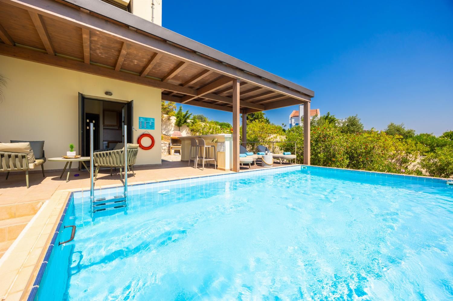 A clear blue pool with lounge chairs and a covered seating area.