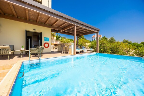 A clear blue pool with lounge chairs and a covered seating area.