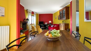 Un comedor con mesa de madera, sillas y una cesta de frutas.