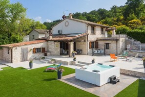 Ein zweistöckiges Steinhaus mit Swimmingpool, Sitzgelegenheiten im Freien und einer Treppe, die zu einem Balkon führt.