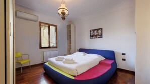 Un dormitorio con una cama, una ventana, una silla y un radiador.