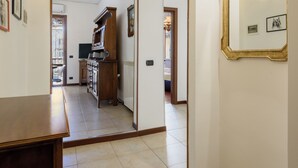 Un pasillo con una mesa de madera, una zona de cocina con estufa y un espejo en la pared.