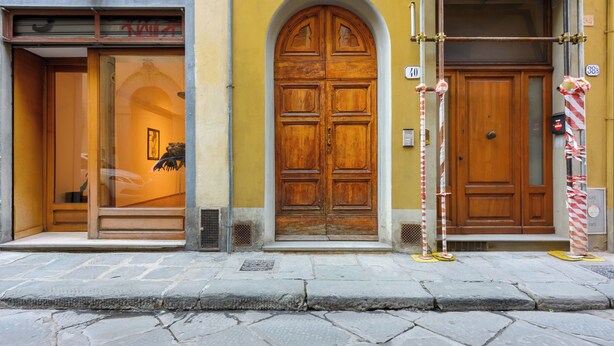 Fachada de edificio con un gran puerta doble de madera, un escaparate y una señal de calle.