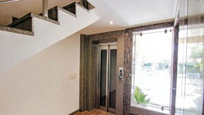 A staircase leading to an elevator, with a view of the outside through a glass door. - Hotel Divine Residency by JMD Group (New Delhi)