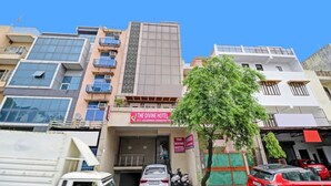 A hotel with multiple floors, a prominent signboard, and a tree in the foreground. - Hotel Divine Residency by JMD Group (New Delhi)