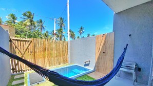 A hammock tied between two buildings, a small pool, and a wooden fence with palm trees in the background. - LOFT Mar 101 - Private Pool - Just Steps from Gastronomic Villages (Tatuamunha)