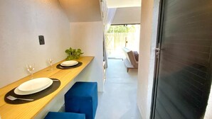 A narrow corridor with a wooden counter on the left, two blue cushioned seating areas, and a sliding glass door on the right. - LOFT Mar 101 - Private Pool - Just Steps from Gastronomic Villages (Tatuamunha)