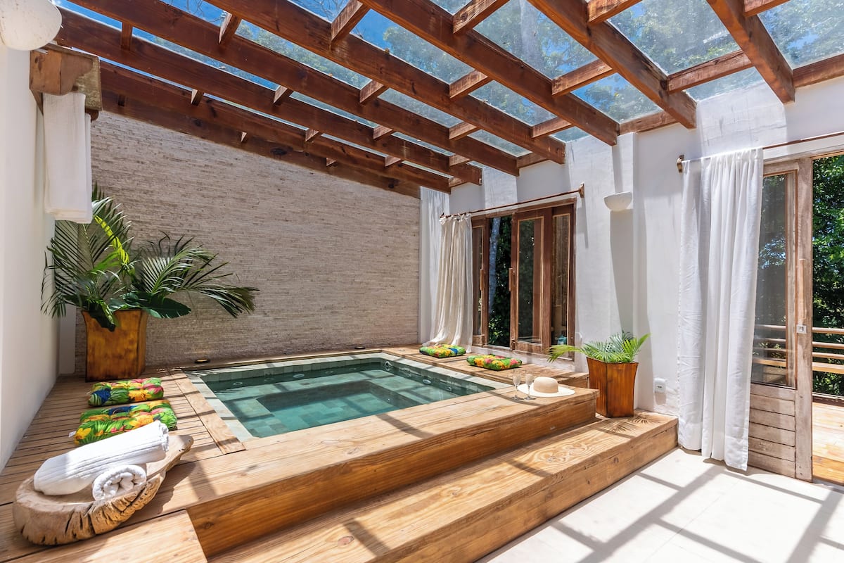 A wooden deck with a hot tub, potted plants, and a towel rack.