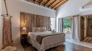 A spacious bedroom with a large bed, wooden headboard, and a view of the outdoors. - Residência Flora (Porto Seguro)