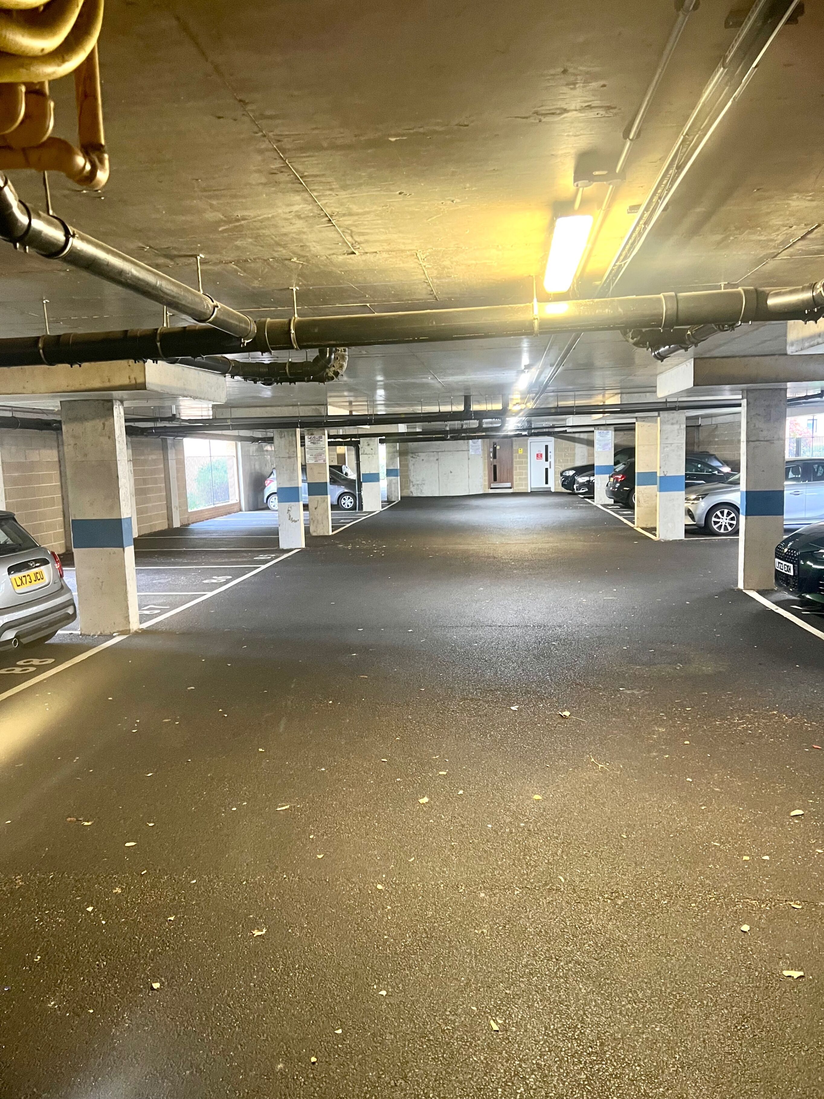 Un parcheggio multipiano con pilastri in cemento, posti auto delimitati e illuminazione a soffitto.
