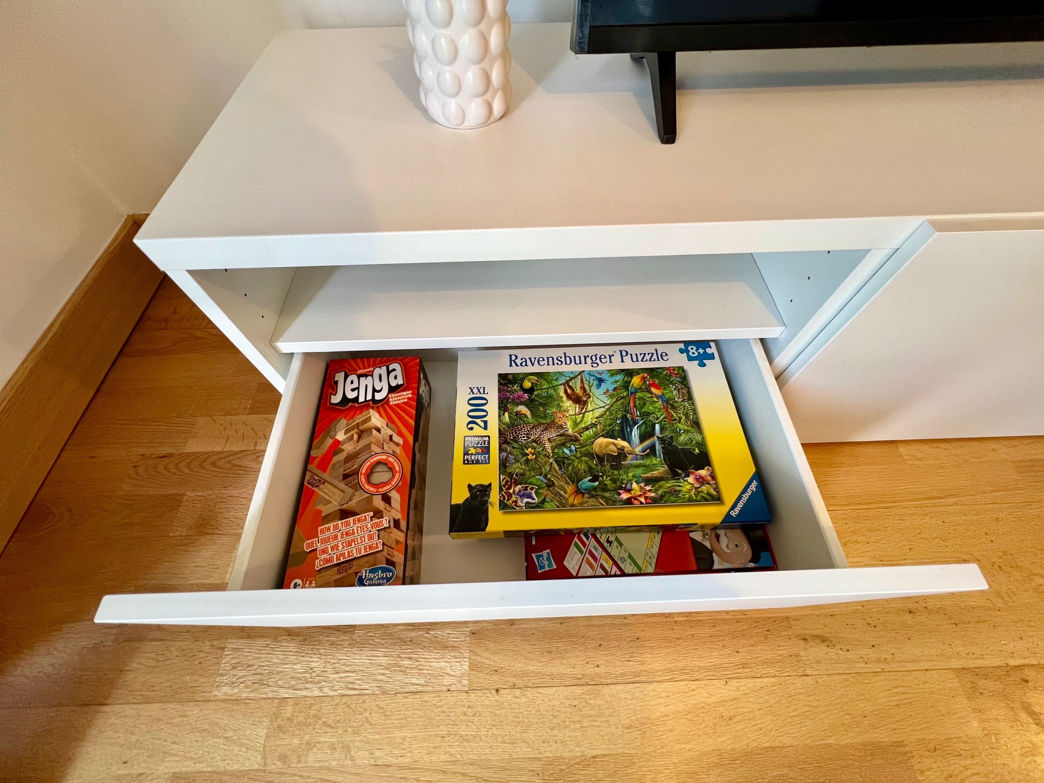 A drawer with a Jenga game and a Ravensburger puzzle box.