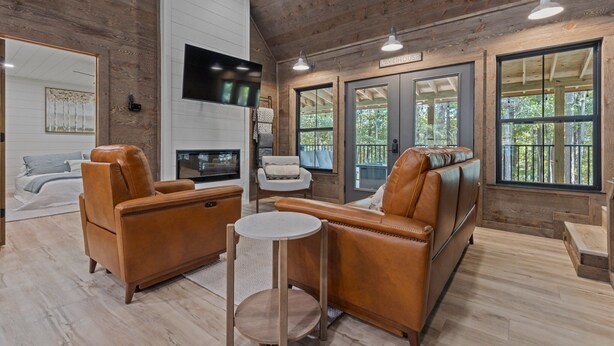 A cozy cabin interior with a large sofa, armchairs, a flat-screen TV, and a fireplace. - Ozark Shores- Lakefront, Hot Tub, Air Hockey (Shirley)