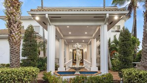 A covered outdoor area with a fountain, palm trees, and a staircase leading to a building entrance. - Villa Tortuga: 10 BR 9,500 sq. ft Extravagant Miami Estate w pool, movie theater (Miami)