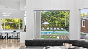 A modern interior with a dining area, a pool view, and a seating area with a view of the pool. - Villa Tortuga: 10 BR 9,500 sq. ft Extravagant Miami Estate w pool, movie theater (Miami)