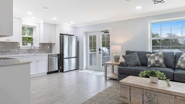 A modern kitchen with white cabinets, stainless steel appliances, and a grey floor. - Water side Upstairs Condo in Sebastian FL (Sebastian)