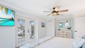 A bedroom with a large bed, a ceiling fan, a wardrobe, and a door leading to a balcony. - Water side Upstairs Condo in Sebastian FL (Sebastian)