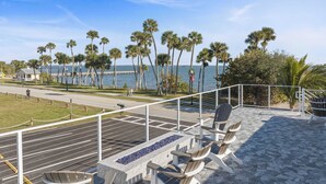 A terrace with outdoor seating, a view of the sea, and palm trees. - Water side Upstairs Condo in Sebastian FL (Sebastian)
