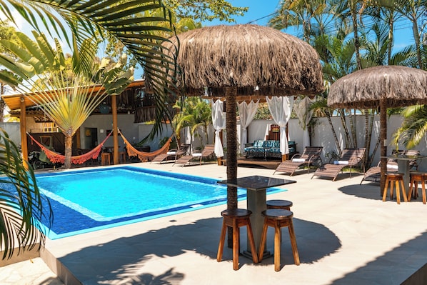 Una piscina al aire libre, sombrillas, sillones reclinables de piscina