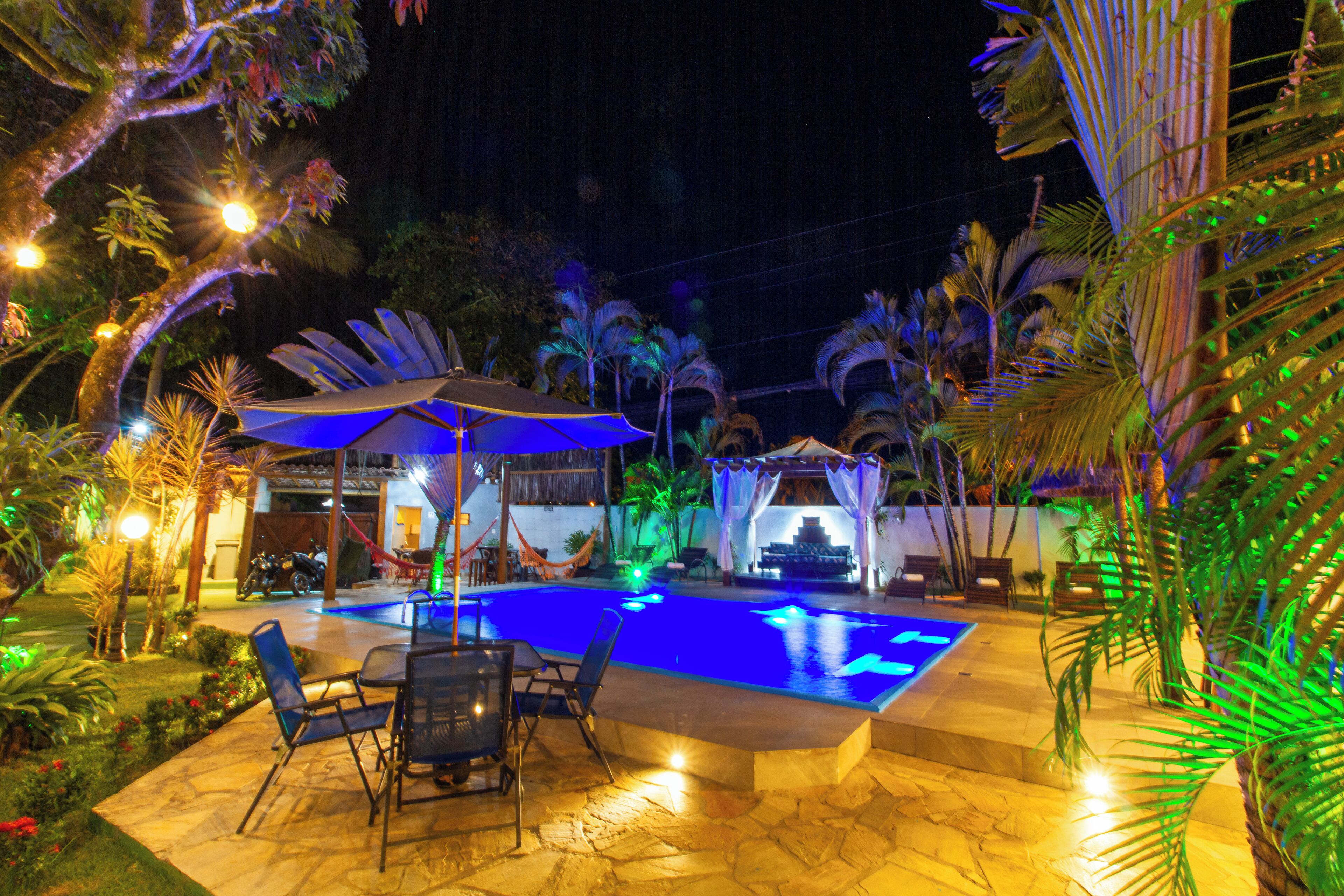 An outdoor swimming pool area with a seating arrangement and a covered area with a table and chairs.