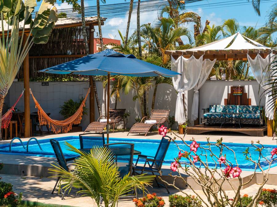 Un área de piscina con sillas de descanso, una hamaca y una zona de estar cubierta con vistas a la piscina.