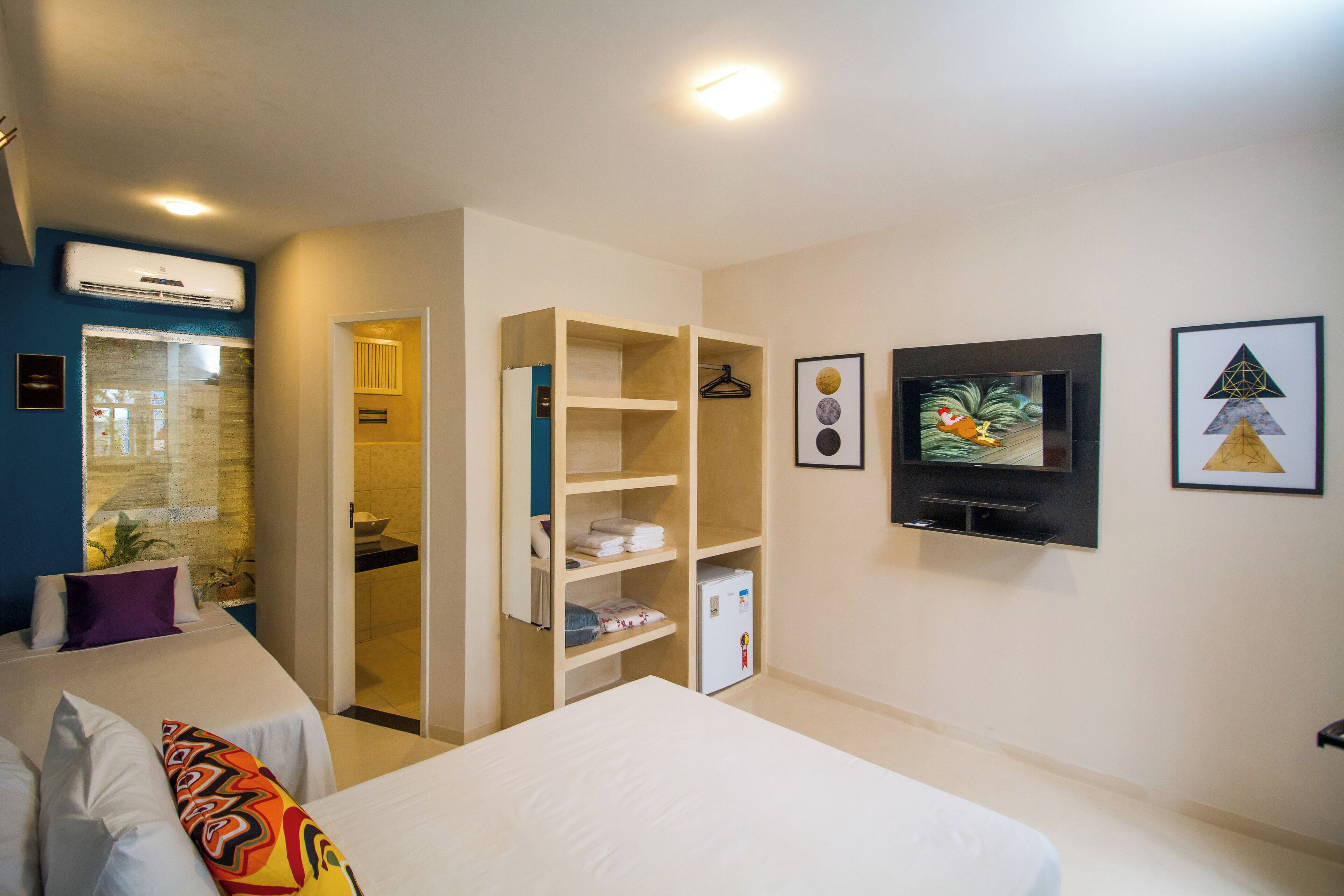 Ett hotellrum med en säng, en garderob, en tv och ett badrum som syns genom en öppen dörr.