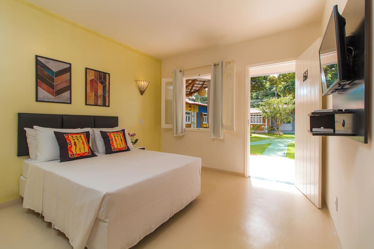 A bedroom with a bed, a TV, and a window with curtains.