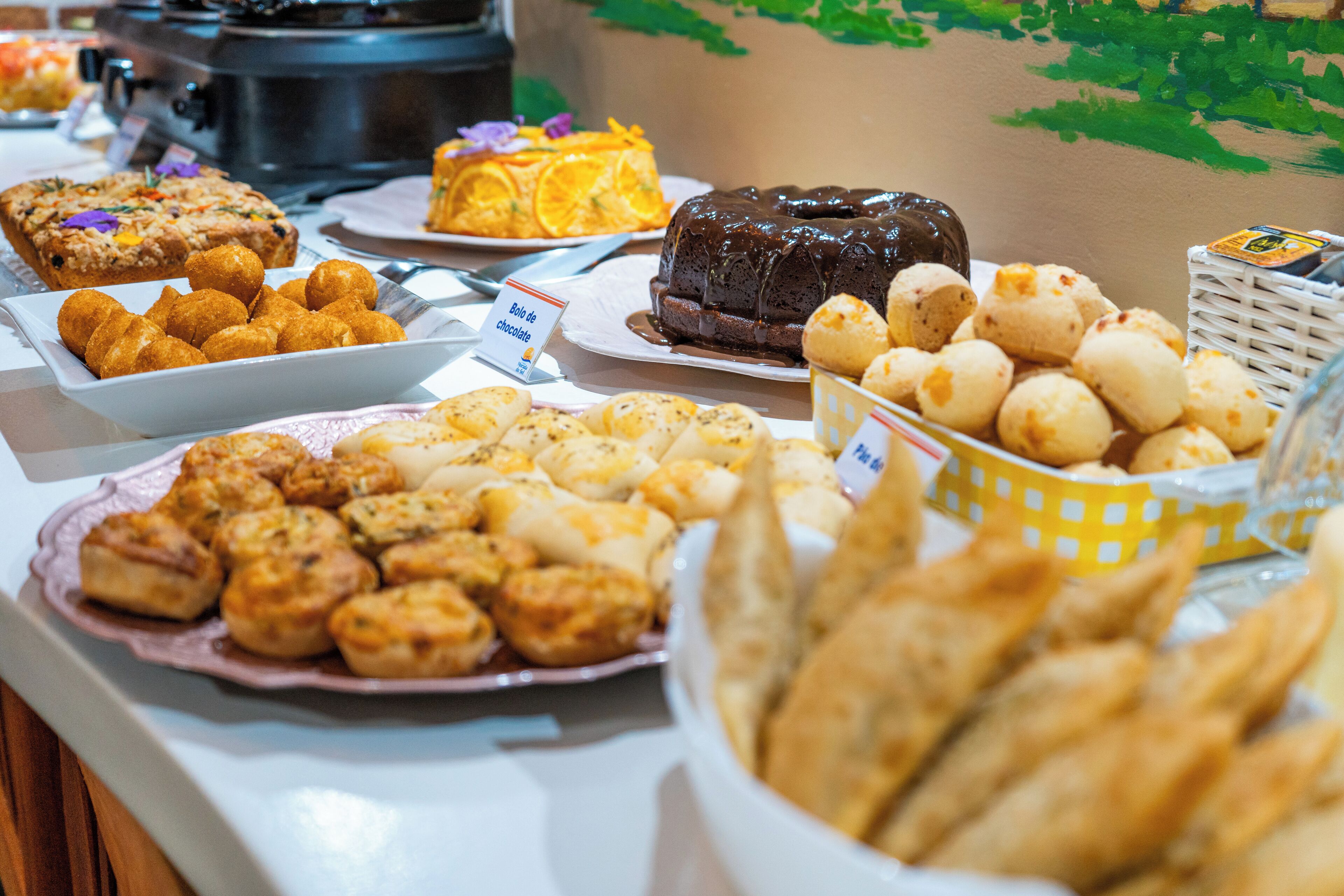 A buffet with various food items including pastries, cakes, and a chocolate cake.