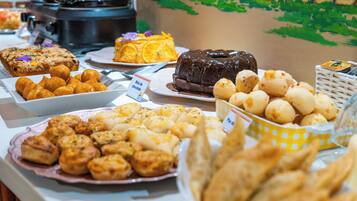 A buffet with various food items including pastries, cakes, and a chocolate cake.