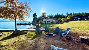 A lakeside property with a dock, a fire pit, and Adirondack chairs. - Lakefront Estate w/ Private Beach on Flathead Lake (Lakeside)