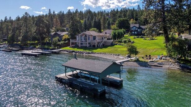 A lakeside property with a dock, a large house, and a well-maintained lawn. - Lakefront Estate w/ Private Beach on Flathead Lake (Lakeside)